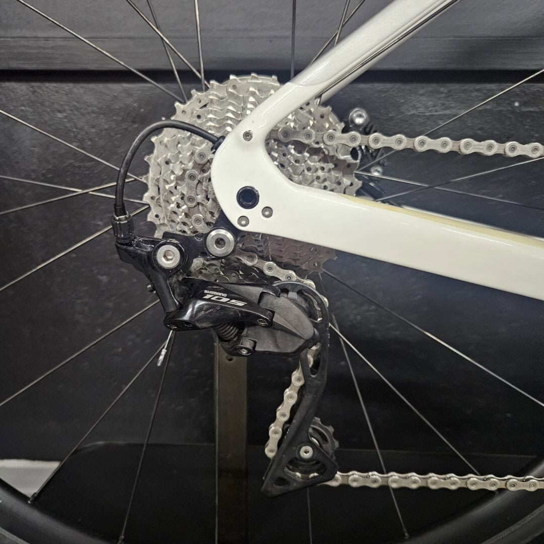 Close-up of a bicycle rear derailleur, cassette, and chain on a gray frame area.
