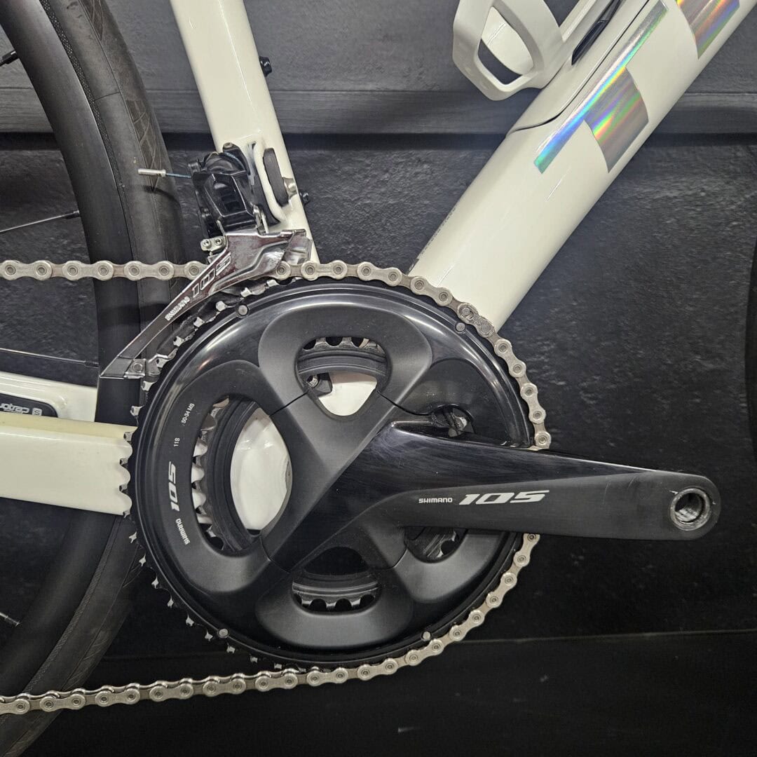 Close-up of a road bike's front crankset and chainring with Shimano 105 branding visible on the crankarm.