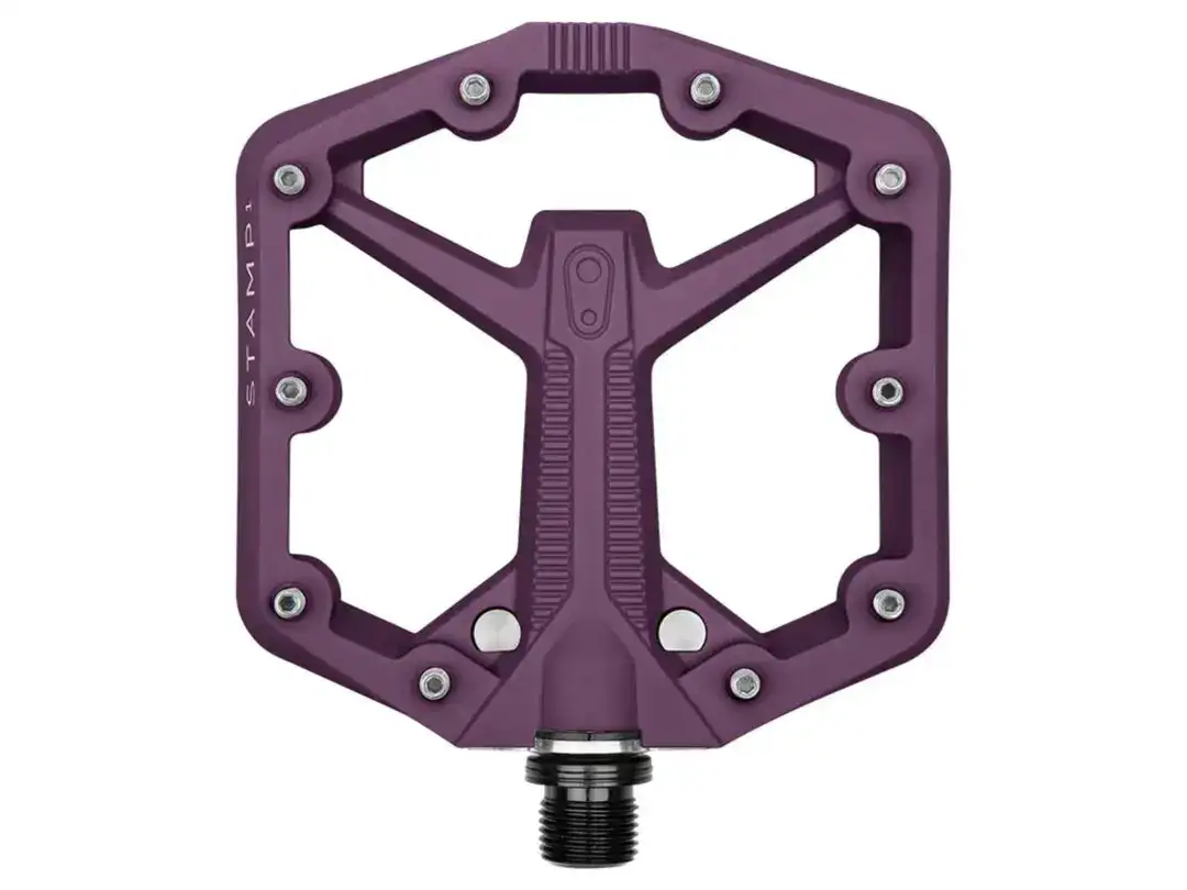 Purple platform bicycle pedal with metal pins, shown attached to the spindle—designed for grip in mountain biking.