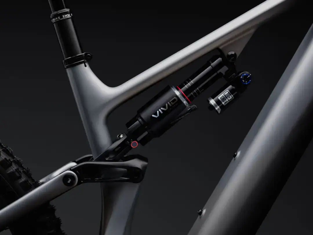 Close-up of a full-suspension mountain bike frame showing the rear shock and seat tube against a dark background.