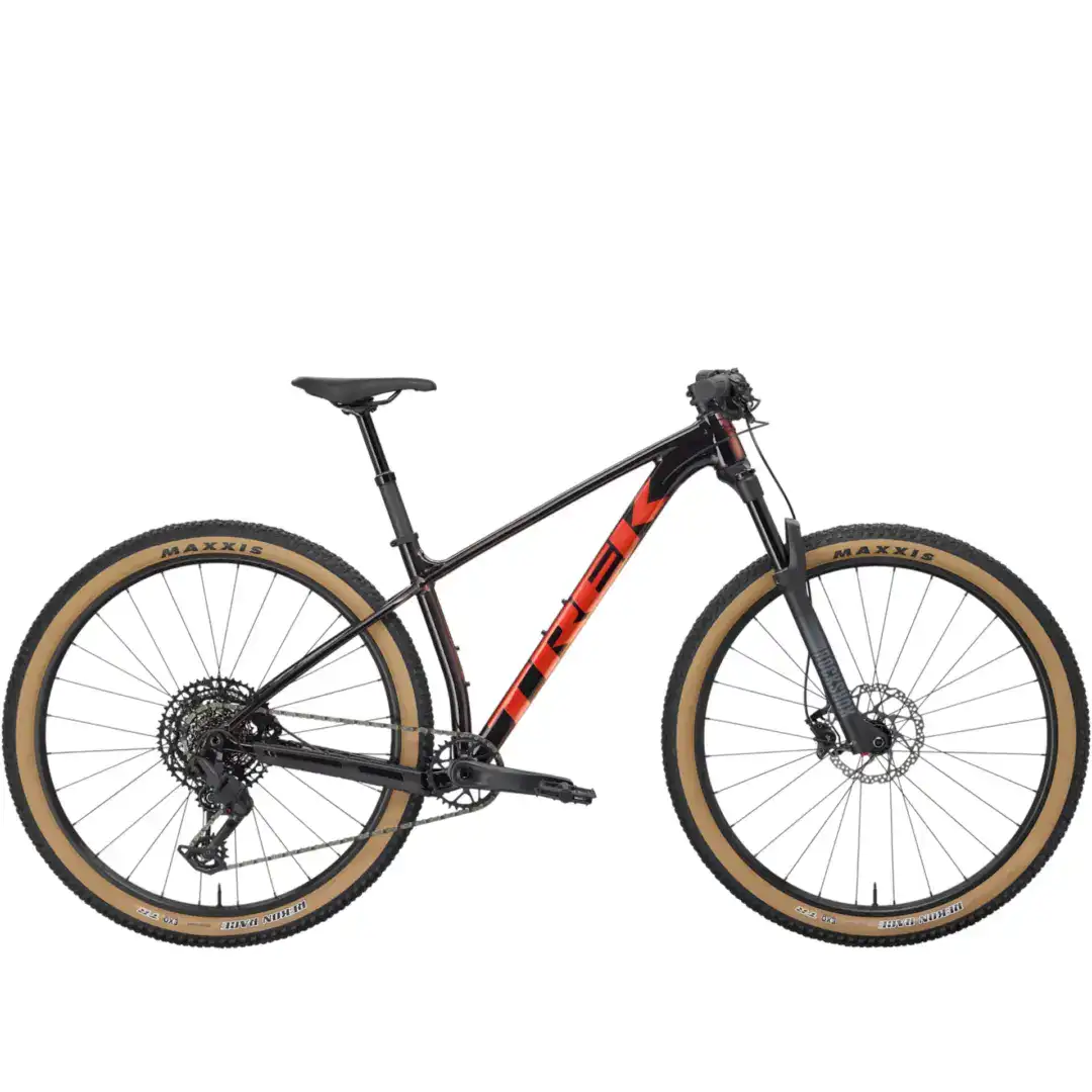Full-suspension mountain bike in black with red accents, tan sidewall tires, and disc brakes visible from the frame and front wheel moment.