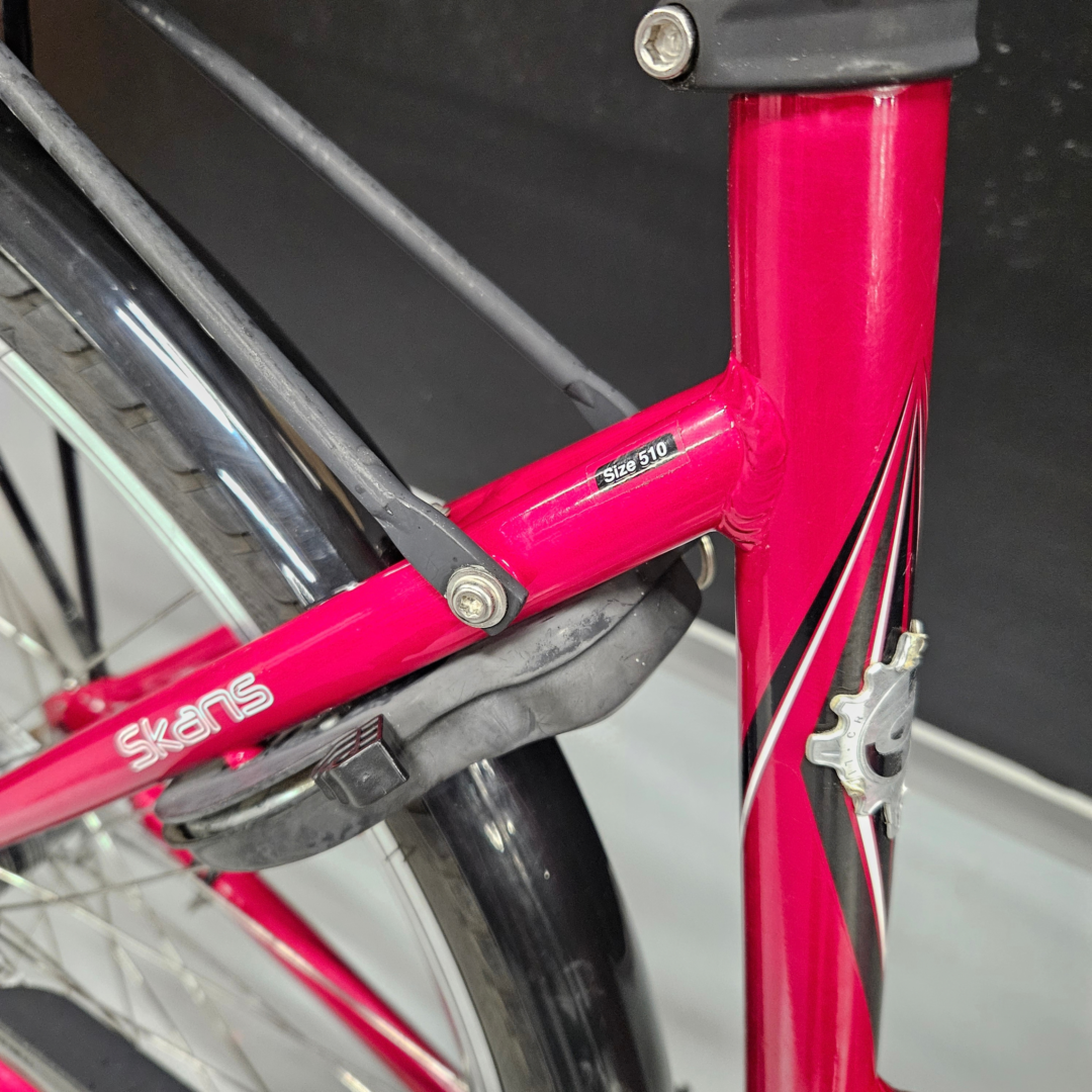 Close-up of a red bicycle frame with black tires and visible cables, showing frame joints and bolts