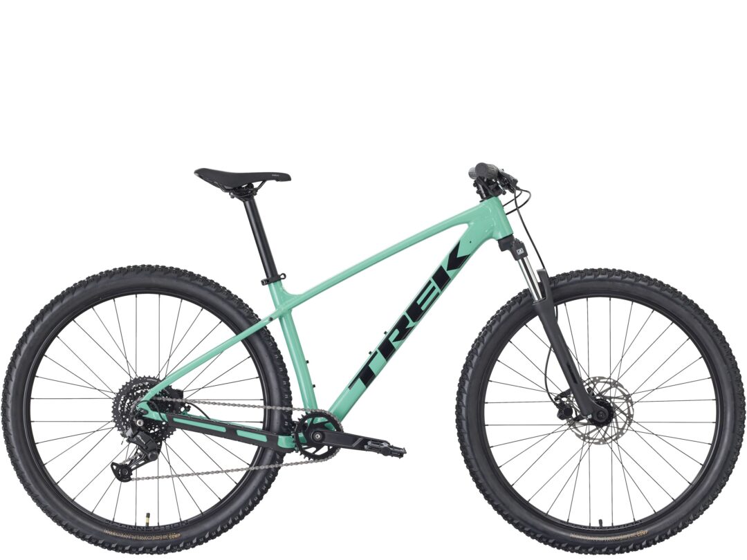 Side view of a mint-green mountain bike with black knobby tires and front suspension fork.