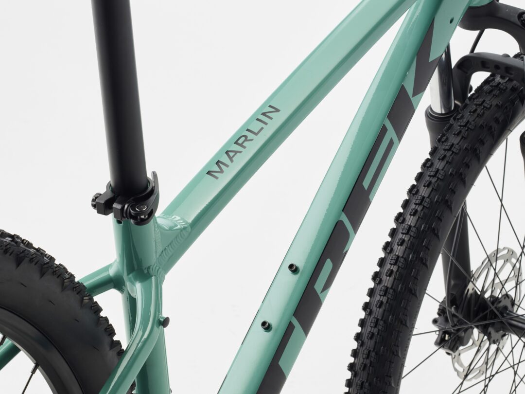 Close-up of turquoise bicycle frame with 'MARLIN' branding and knobby tires, partial fork and handlebars visible