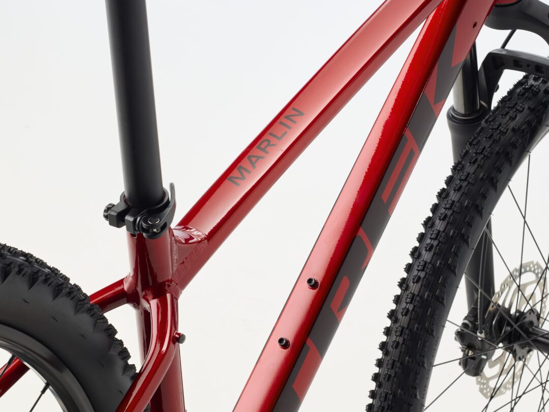 Close-up of a glossy red mountain bike frame with a black front suspension fork and knobby tire with a visible disc brake rotor.