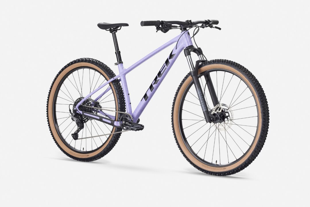 Purple hardtail mountain bike with tan tires and front suspension against a white background.