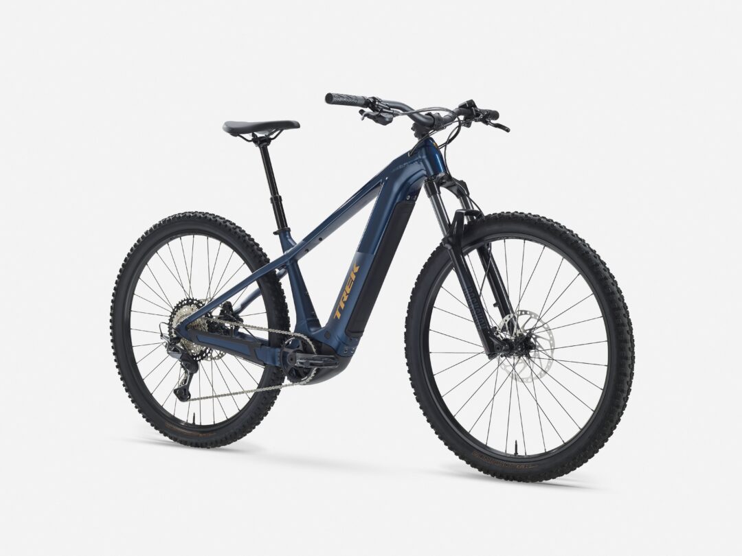 Blue mountain bike shown from the side with knobby tires and front suspension against a white background.