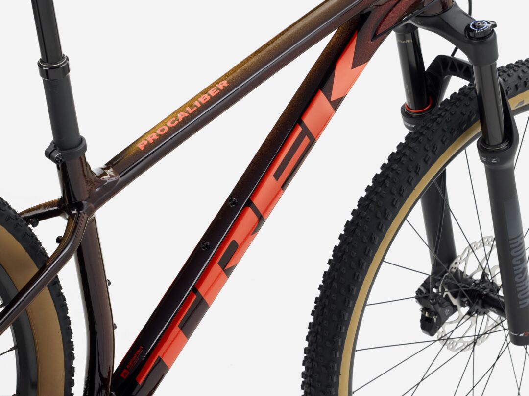 Close-up of a mountain bike frame with 'PRO CALIBER' decals, showing the front suspension fork and a knobby tire.