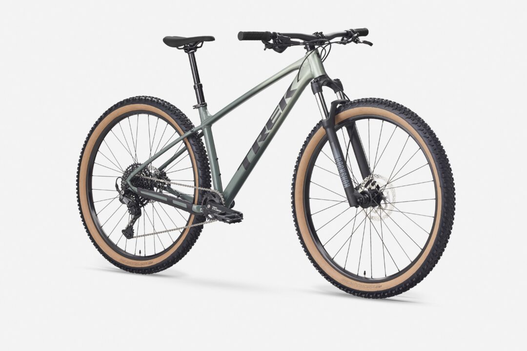 Side view of a gray-green mountain bike with tan-wall tires and a front suspension fork against a white background.