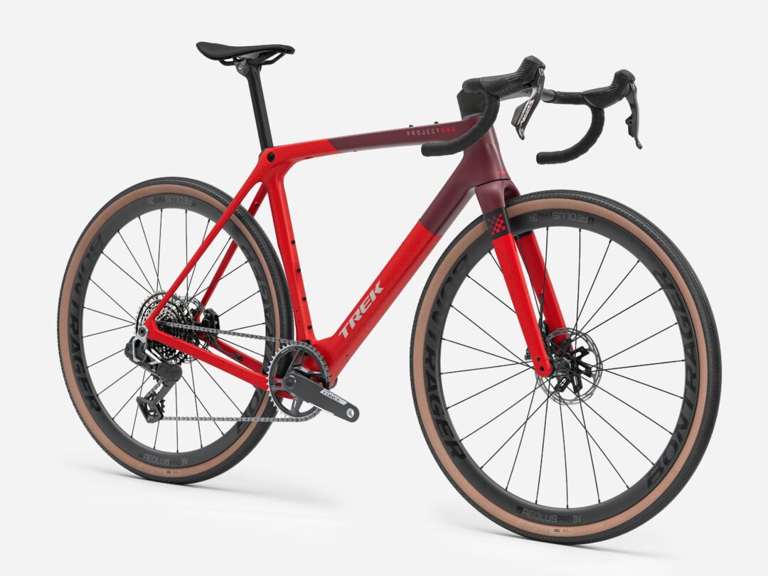Red Trek road bike with carbon frame, drop handlebars, and tan sidewall tires (Project One).