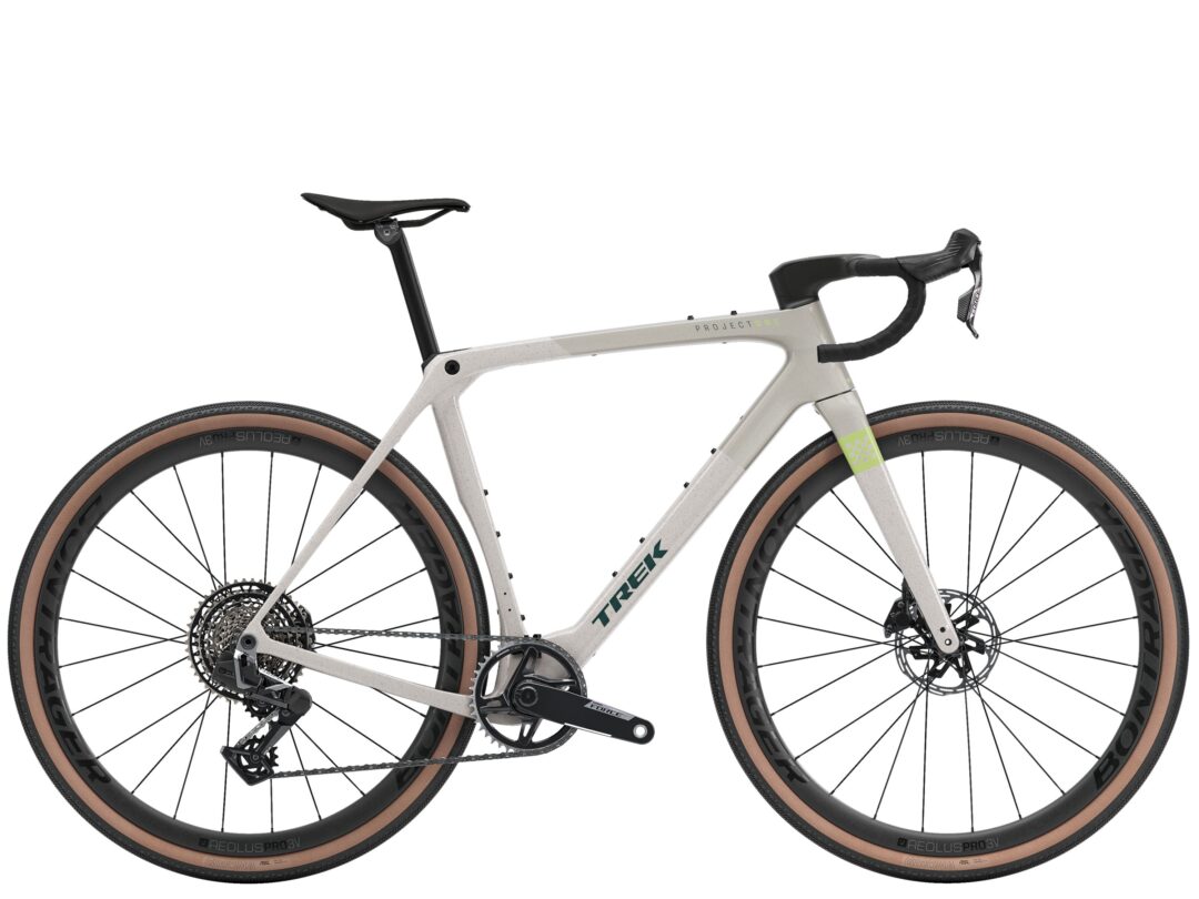Side view of a beige Trek gravel bike with drop handlebars, large brown-tan tires, and disc brakes