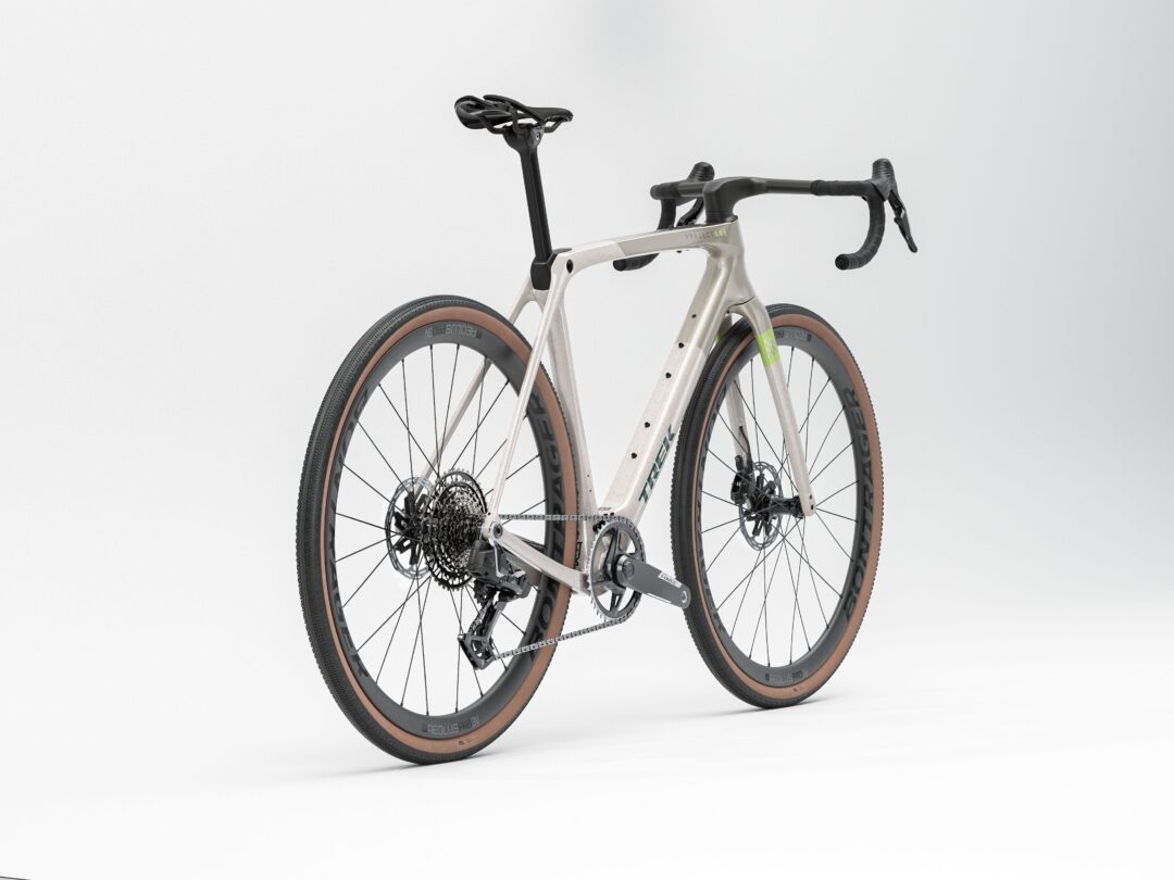 Side view of a modern gray road bike with drop handlebars and brown-tan tires against a white background.