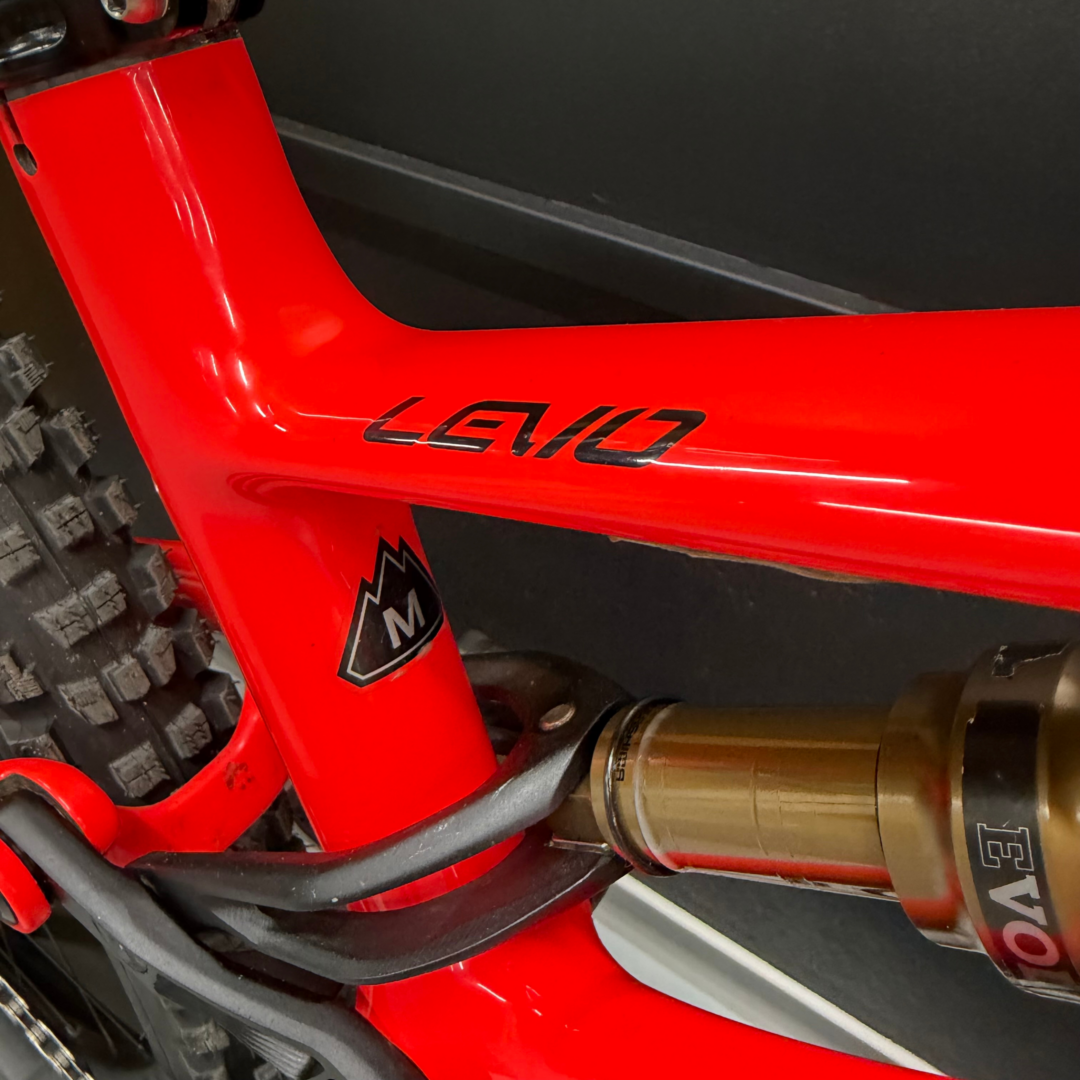 Close-up of a glossy red bicycle frame with visible black lettering and a knobby tire in the corner.
