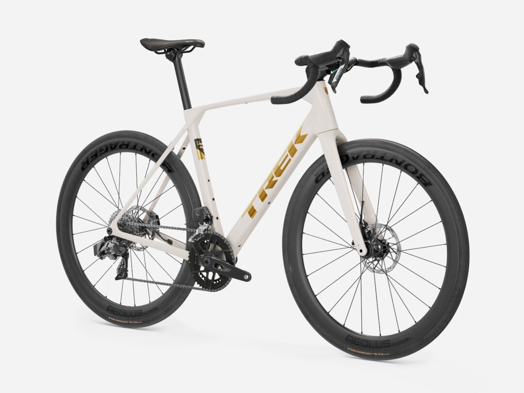 Cream-colored road bike with drop handlebars and large aero wheels, showing drivetrain and rear cassette