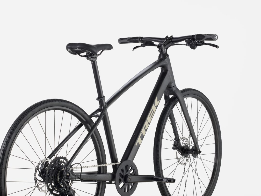 Close-up of a black bicycle showing the drivetrain, rear wheel, and handlebars.