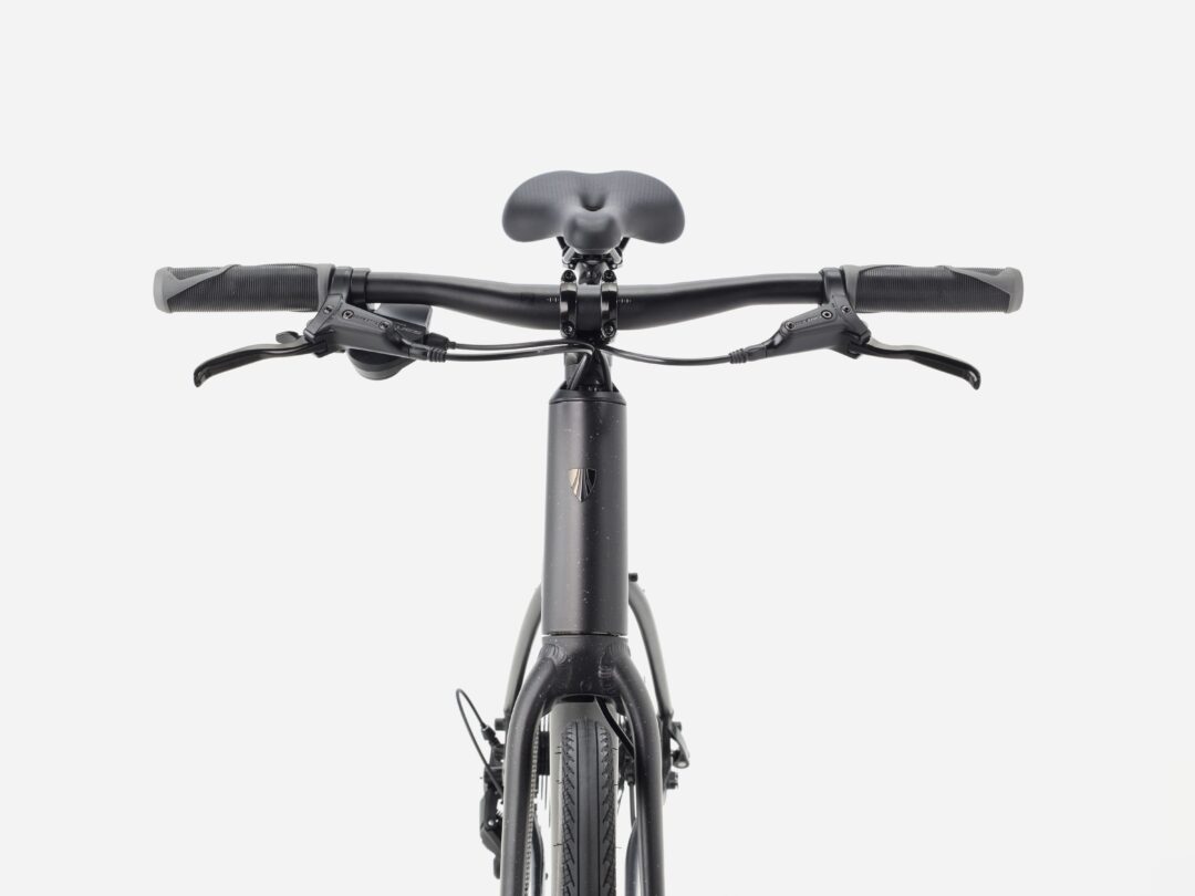 Front view of a black bicycle with wide handlebars, brake levers, and grips, seen against a white background.