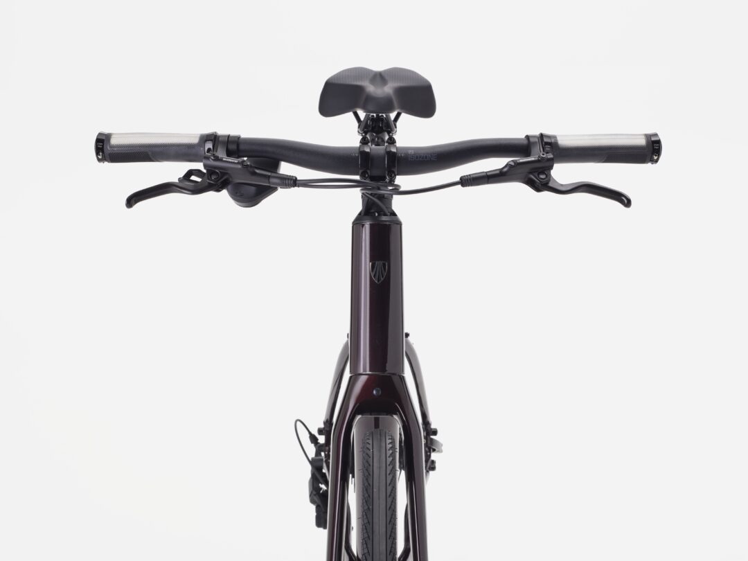 Top-down view of a black bicycle cockpit with handlebars, brake levers, and saddle visible against a white background.