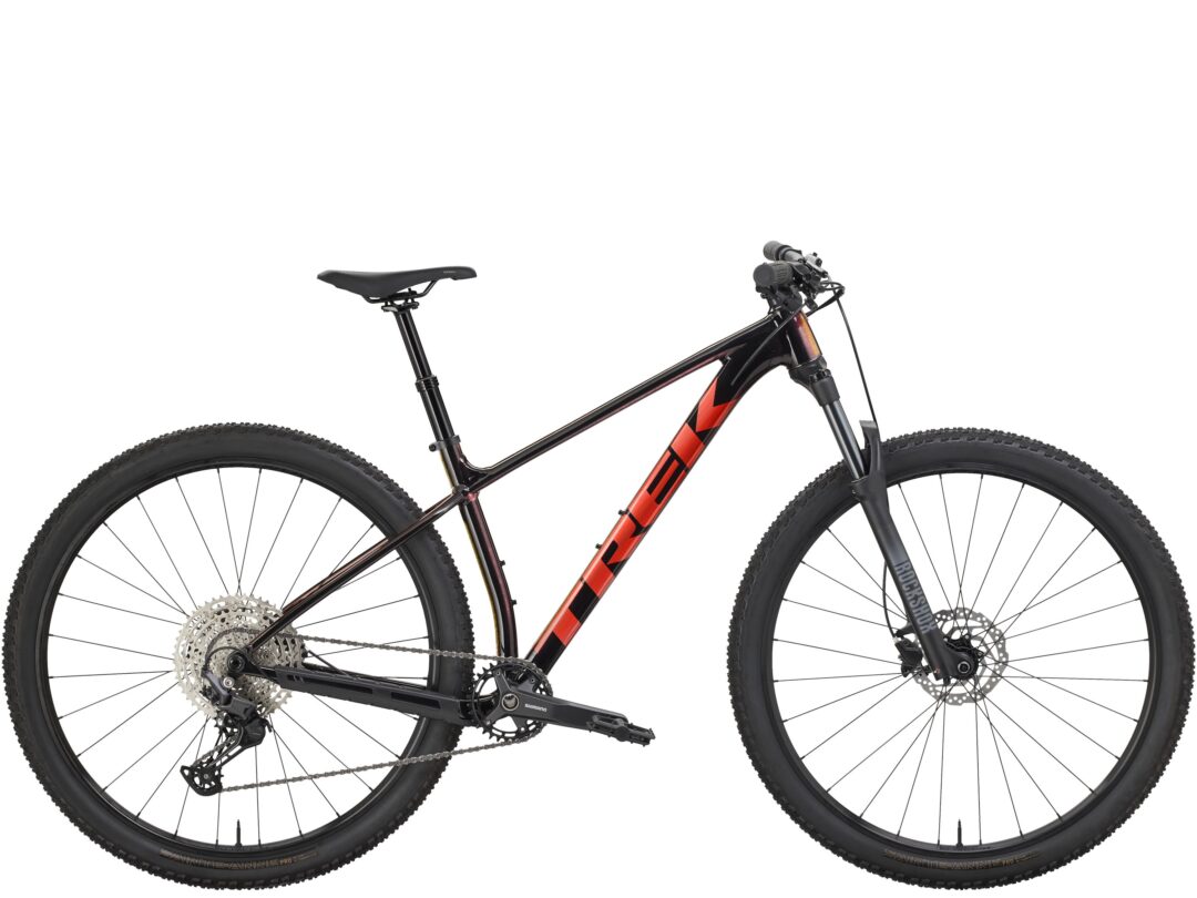 Mountain bike shown from side with black frame and red decals, front suspension, disc brakes, and wide knobby tires on both wheels.